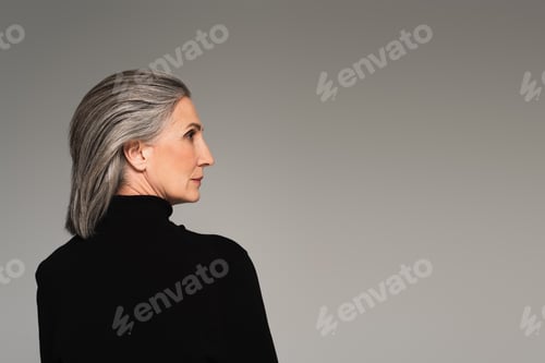 Preview: Side view of mature woman in turtleneck looking away isolated on grey