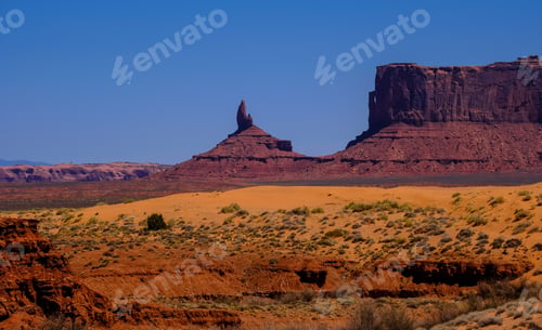 Preview: Desert hill with dried bushes and cliffs in the distance on a sunny day