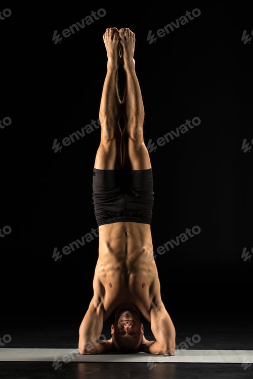 Preview: Man performing Sirsasana or Yogic Head Stand on yoga mat isolated on black