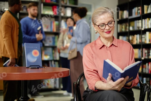 Preview: Senior Caucasian Woman Reading Book in Library Setting