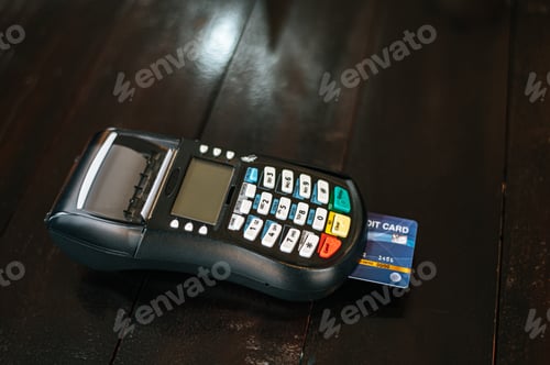 Preview: Card machine or pos terminal with inserted credit card on wood table