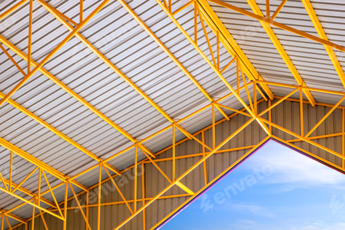 Preview: yellow metal roof beams and aluminum corrugated tile roof of industrial building with blue sky