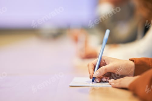 Preview: Picture of a human hand writing something on the paper on the foreground