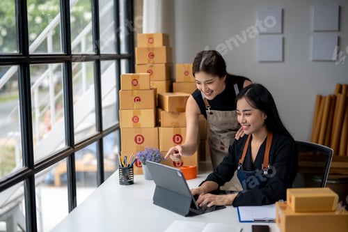 Preview: Two women are sitting at a desk with a laptop