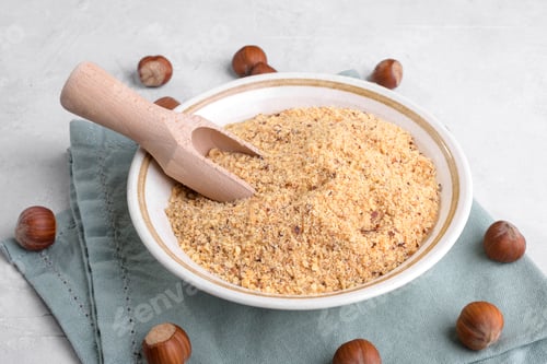 Preview: Raw Organic Ground Hazelnut Flour in a Bowl with whole nuts on grey table