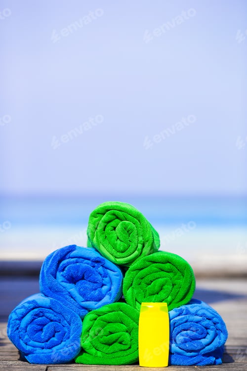 Preview: Close up of colorful towels and sunscreen bottle background the sea