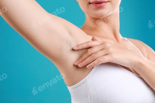 Preview: Young woman with smooth clean armpit on teal background, closeup. Using deodorant