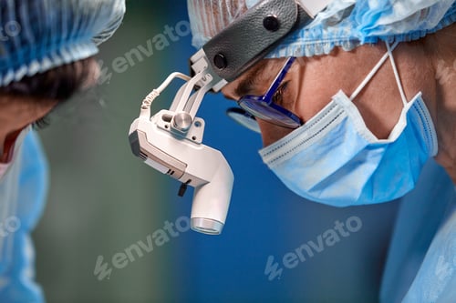 Preview: Surgeon and his assistant performing cosmetic surgery on nose in hospital operating room. Nose