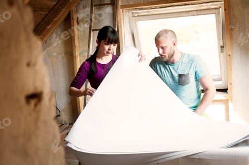 Preview: Two people examining blueprints at a construction site.