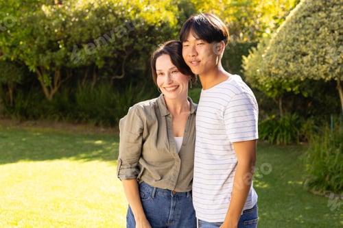 Preview: Smiling mother and teenage son embracing outdoors in sunny garden, enjoying quality time together