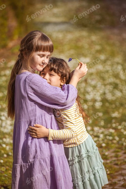 Preview: two little girls of six years old are playing on a flowering lawn,spring, children's fun,girlfriends