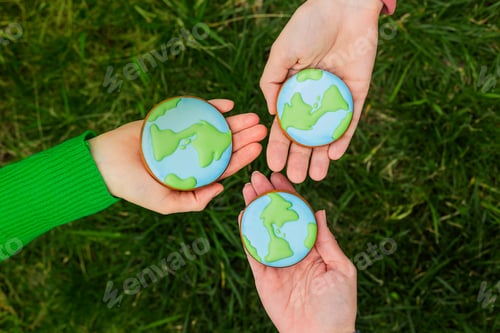 Preview: Earth Day concept. Hands hold gingerbread in the shape of the Earth. Care for the environment.