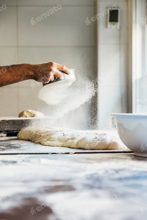 Preview: Baker man hand spreading flour to dough.