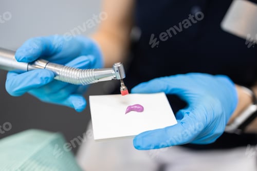 Preview: Close up view hand of a dentist doctor with a dental drill applies a cleaning paste on a brush.
