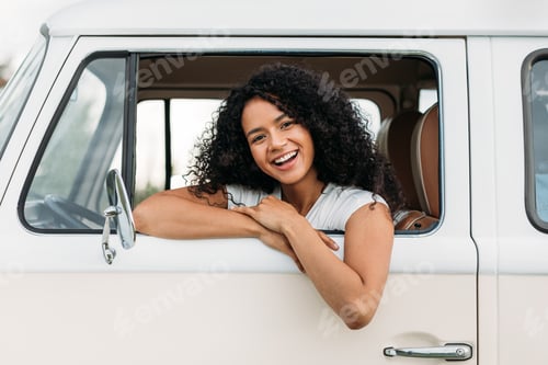 Preview: Attractive mixed race woman enjoying road trip looking at camera
