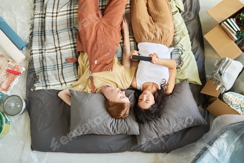 Preview: Above angle of two young affectionate girlfriends watching online video