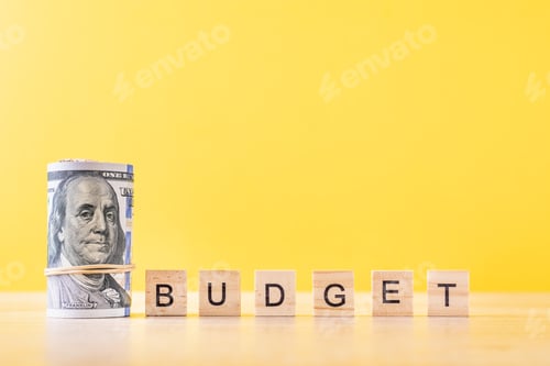 Preview: Rolled up dollar bills and word budget on a yellow background