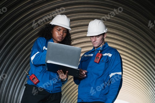 Preview: Workers inside a big steel pipe building a pipeline for oil, gas, and fuel at an industrial site.