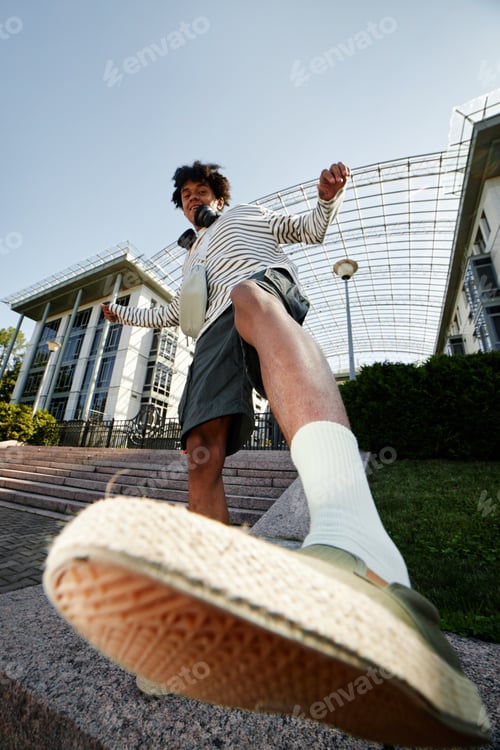 Preview: Teenage Black Boy Kicking Camera while Having Fun Posing Outdoors