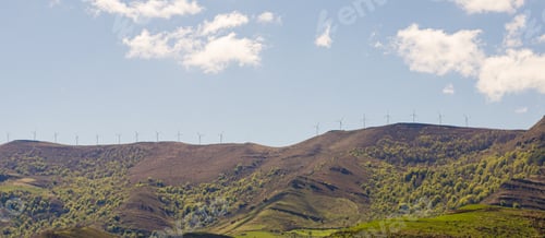 Preview: Windmill farm on mountain slope in sunlight