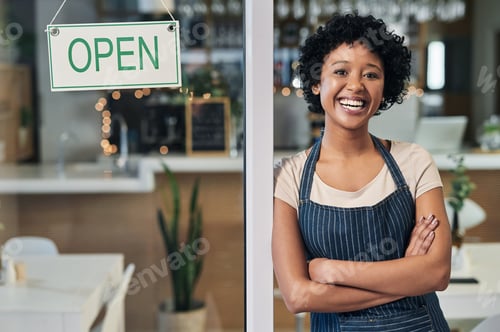 Preview: Portrait of a young woman standing alongside an open sign in a cafe