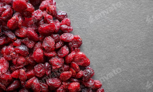 Preview: Close up photo of dried organic cranberries on a dark slate background, selective focus.