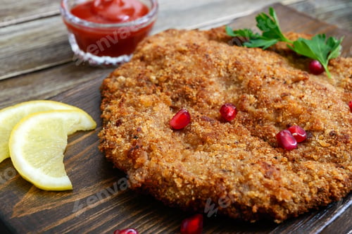 Preview: Large Viennese schnitzel on a wooden background. Meat dish. Close up
