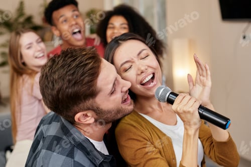 Preview: Sing together. Young excited couple or friends holding microphone and singing together while