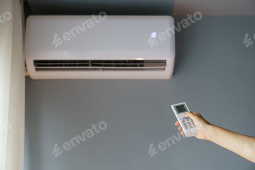 Preview: Owner turns on air conditioner hanging on wall with remote control to warm up cold apartment