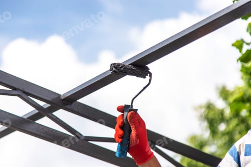 Preview: A man paints metal poles. Selective focus.