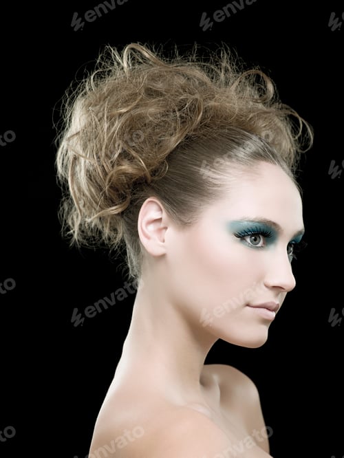 Preview: Woman with striking blue eye makeup and elegant updo against a black background