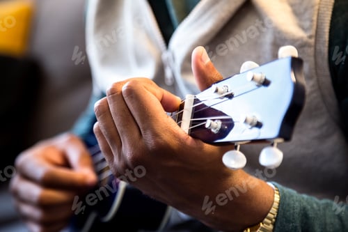Preview: Handsome young black man playing the guitar at home.