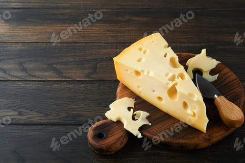 Preview: Cheese. Piece of cheese triangle, Swiss cheese on with basil and a knife on a serving board on dark