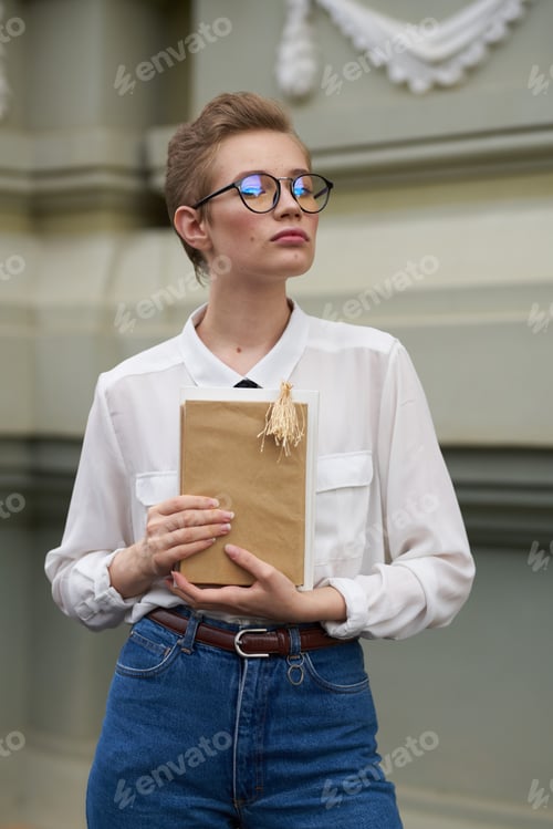 Preview: beautiful woman student with book in hand near building suit model cropped view