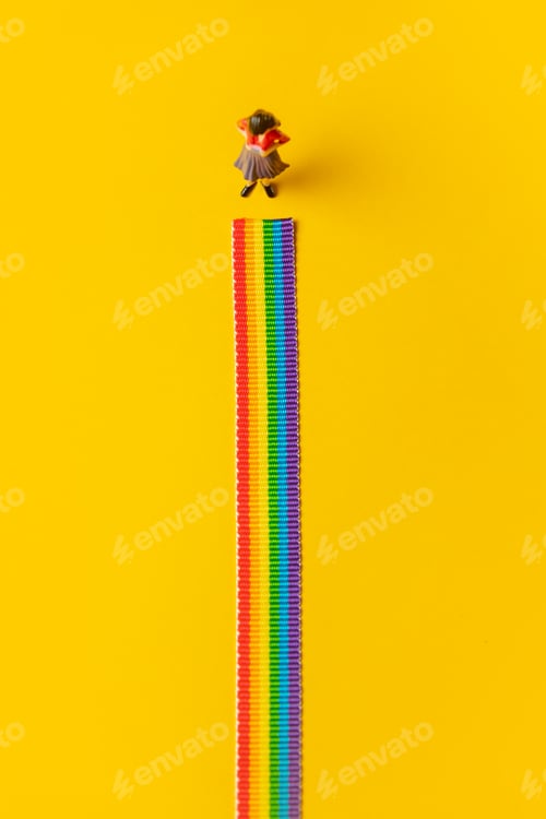 Preview: Adult woman figure stand on rainbow LGBT strip on yellow background