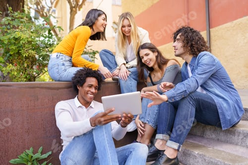 Preview: Multi-ethnic group of young people looking at a digital tablet outdoors in urban background