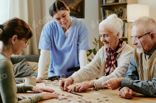 Preview: Senior Woman and Man Solving Puzzle with Nurse Assisting at Table