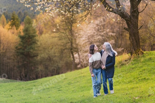 Preview: Happy senior grandmother with teenage granddaguhter on walk in nature on spring day.