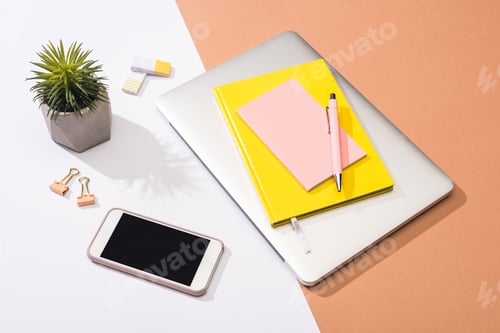 Preview: high angle view of laptop, notebooks, pen, plant, erasers, smartphone, paper clips and paper