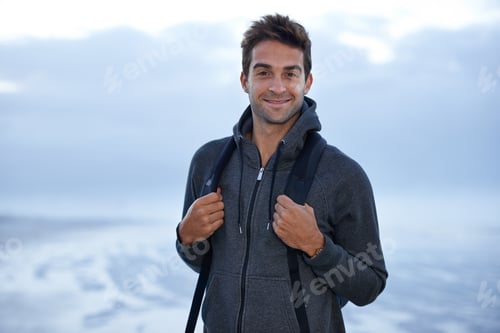 Preview: Here for inspiration. A handsome young man standing on the beach at evening time.