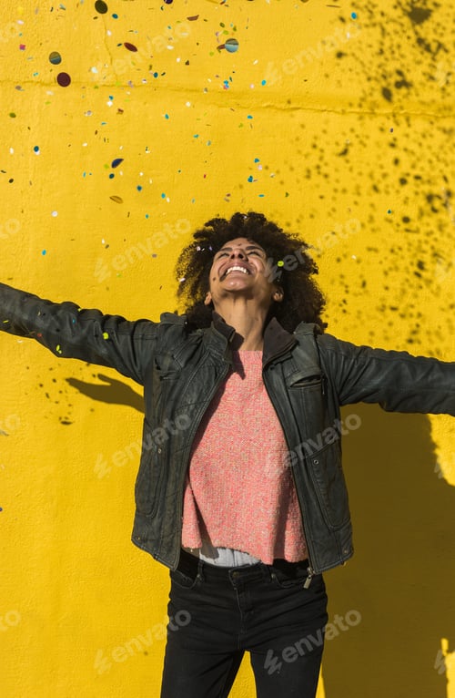 Preview: Black woman with afro hair celebrating with confetti.
