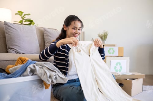 Preview: A young woman separates unused clothes and prepares them for donation or recycling in order to