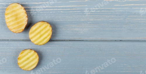 Preview: close-up view of sliced and ruffled potato slices on left side and wooden background with copy space