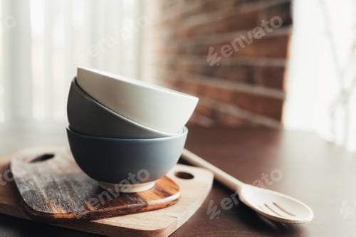Preview: Three ceramic bowls, wooden spoon on a wooden brown table. Blurred background