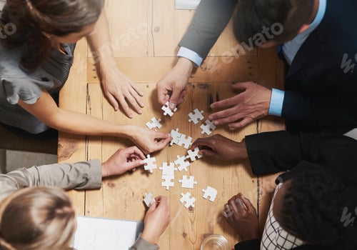 Preview: High angle shot of a group of businesspeople building a puzzle together in an office