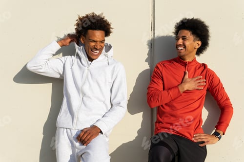 Preview: Happy black friends leaning on street wall together