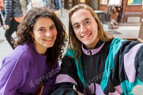 Preview: Two friends taking a selfie while sitting on a table outdoors.