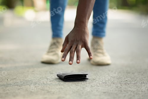 Preview: Close up view of black guy picking up lost wallet on city street