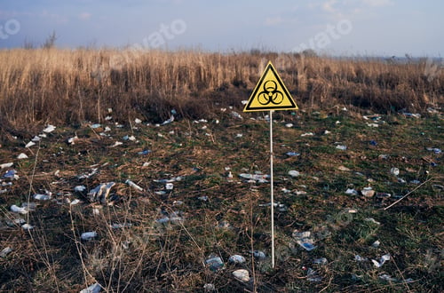 Preview: Warning biohazard sign in field with garbage.
