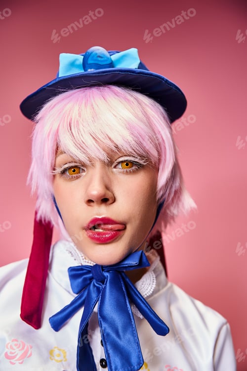 Preview: alluring young female cosplayer sticking out her tongue and looking at camera on pink backdrop